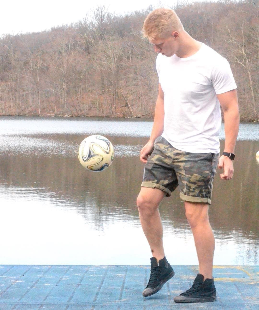 Luke juggling a football by a lake